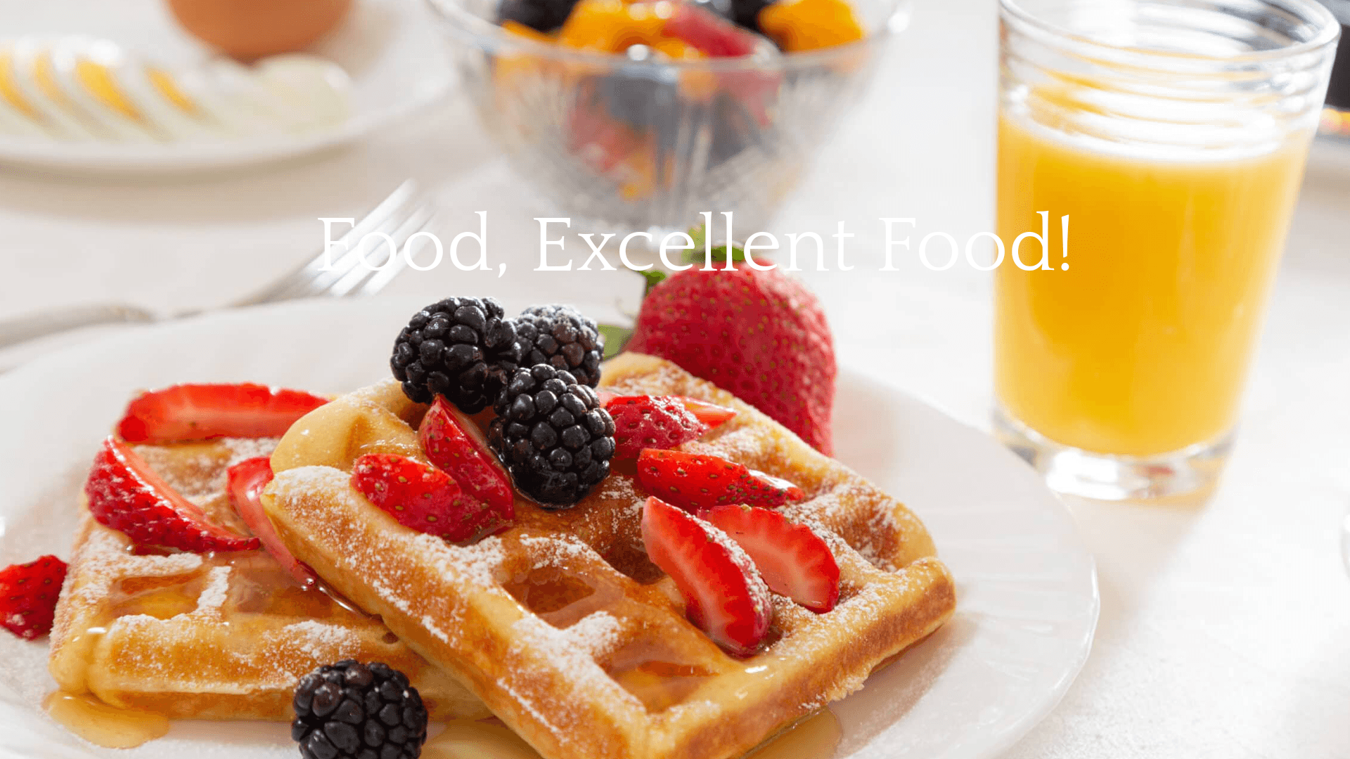 A plate of waffles topped with fresh berries and powdered sugar, accompanied by a glass of orange juice.