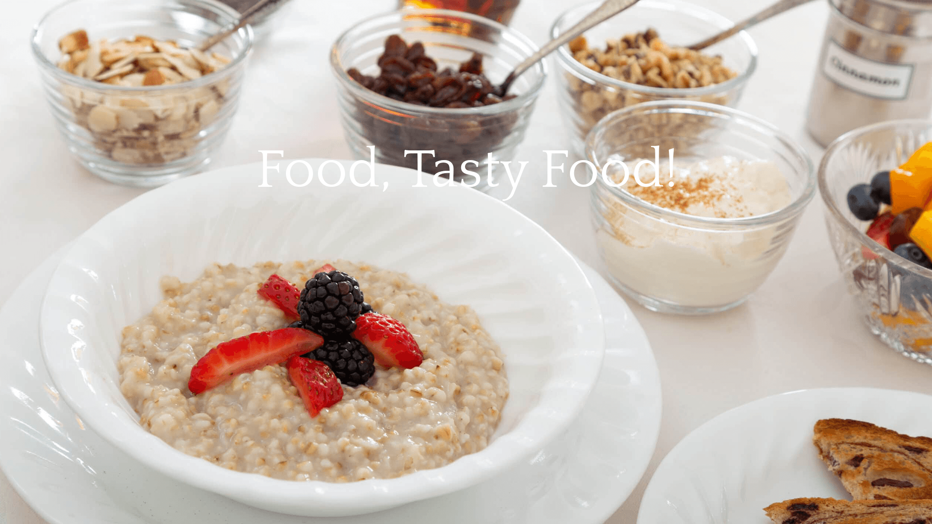 A bowl of oatmeal topped with strawberries and blackberries, surrounded by various toppings and a slice of bread.