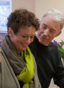 A man and a woman share a warm, smiling moment indoors.